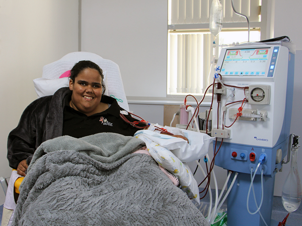 A young girl from the Wangaratta District Specialist School is looking comfortable and relaxed in a reclining chair with a fluffy blanket over her, to keep her warm while she is connected to the dialysis machine.