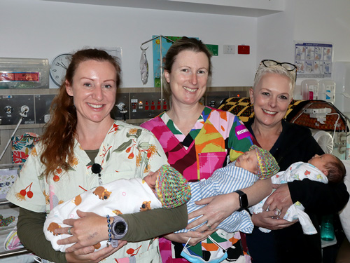 Three midwives holding triplets in NHW nursery unit.