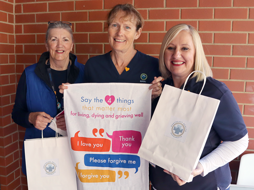 Three ladies from our palliative care team holding up bags containing information about Advance Care Planning.