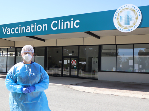 person wearing full PPE standing in front of the NHW vaccination clinic