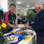 Illoura staff member offering a gentleman sandwiches at Australia's Biggest Morning Tea celebrations at Illoura