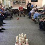 Older lady sat in a chair playing indoor bowls